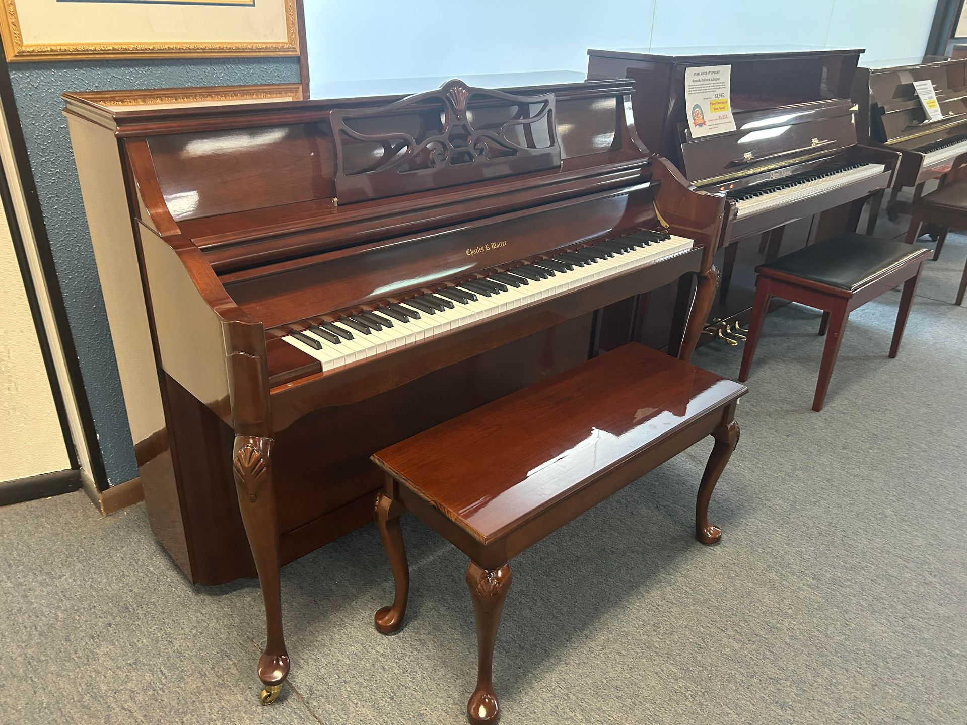 A brown upright piano with a matching bench in a showroom setting.