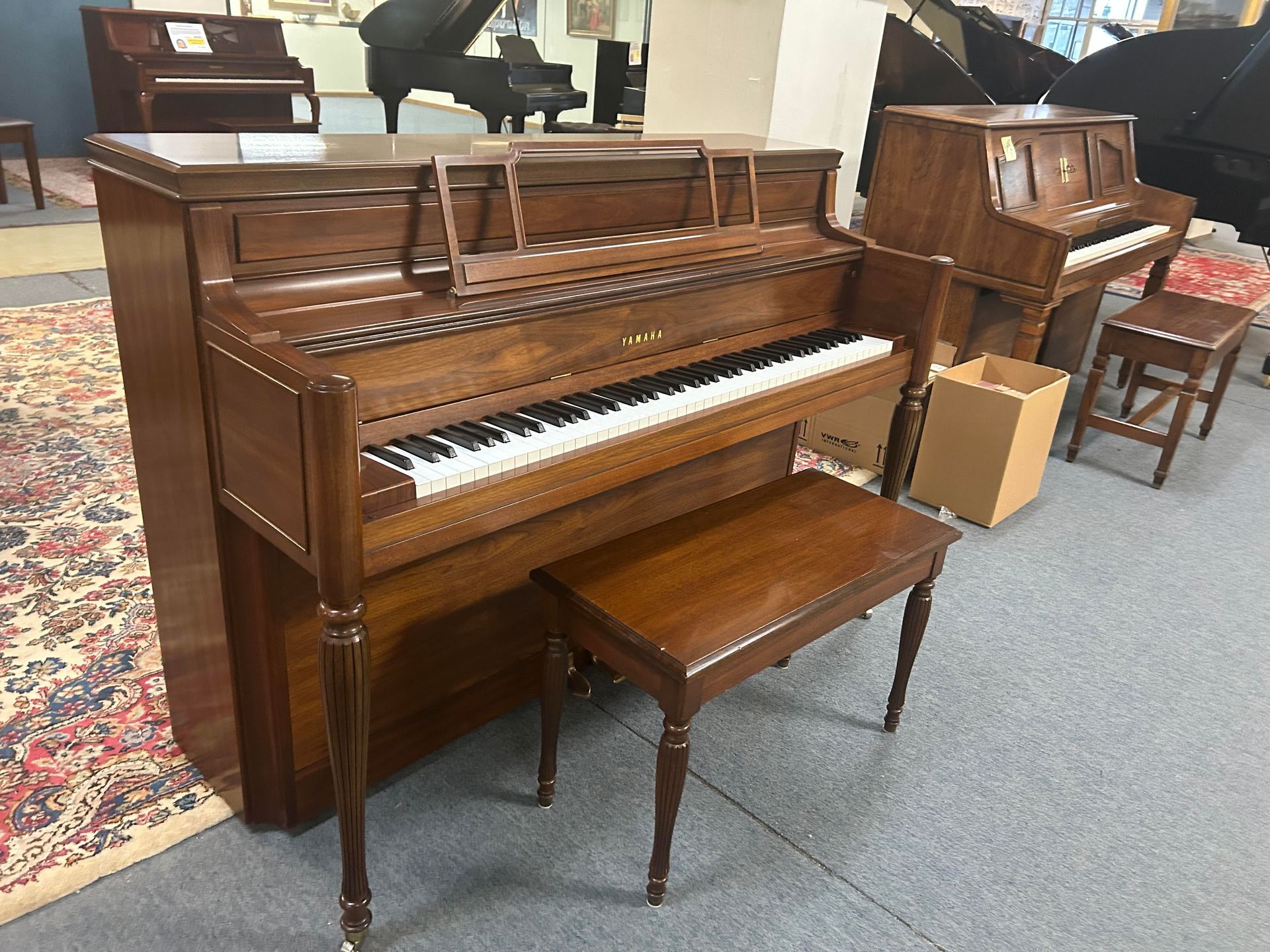 Dark wood upright piano with matching bench in a showroom.
