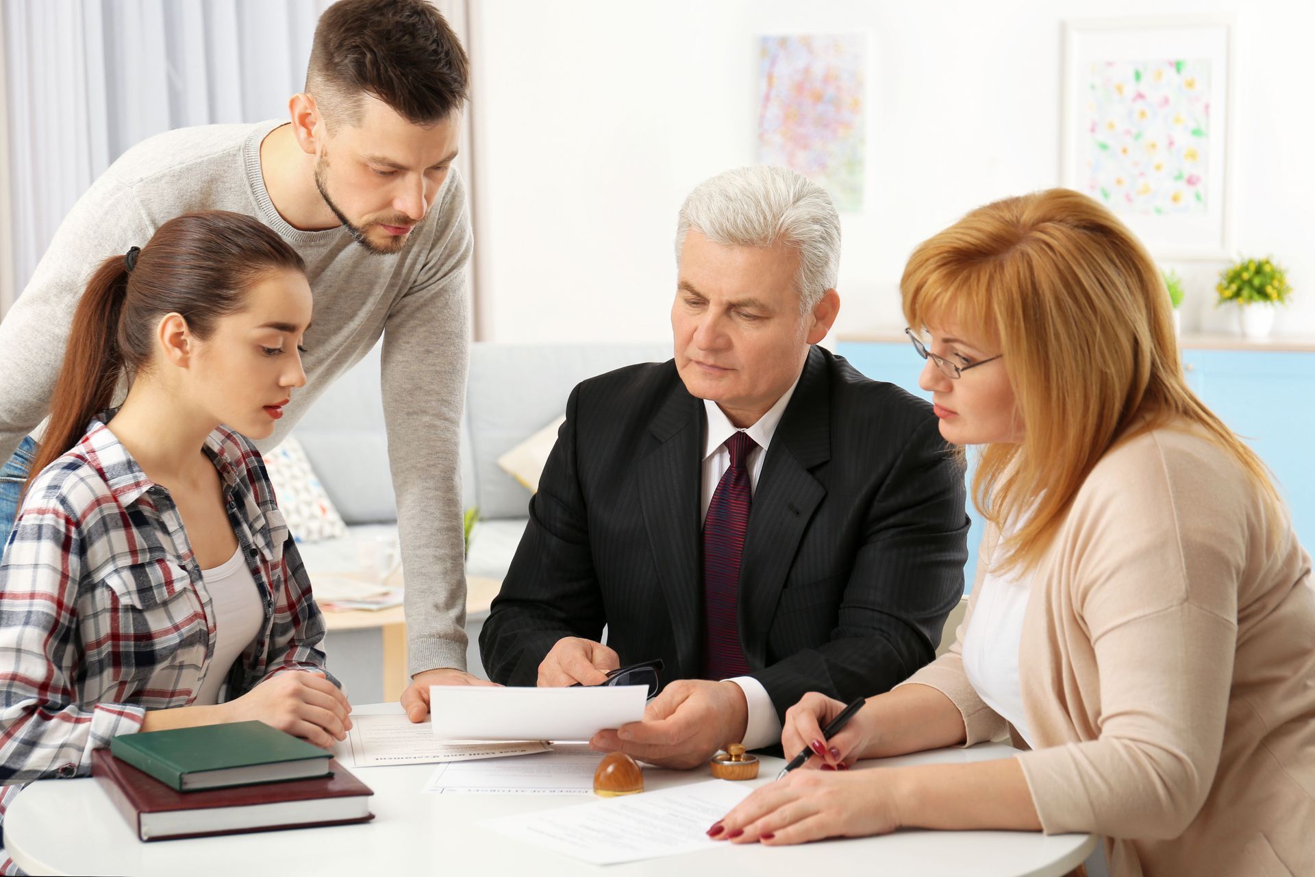 Four people around a table reviewing documents, likely in a business setting.