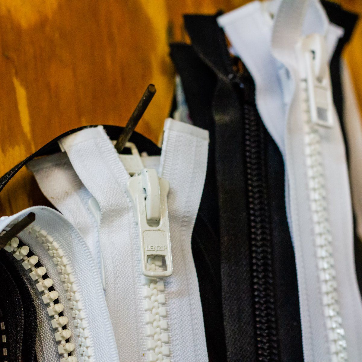 Black and white zippers are hanging on a wooden wall