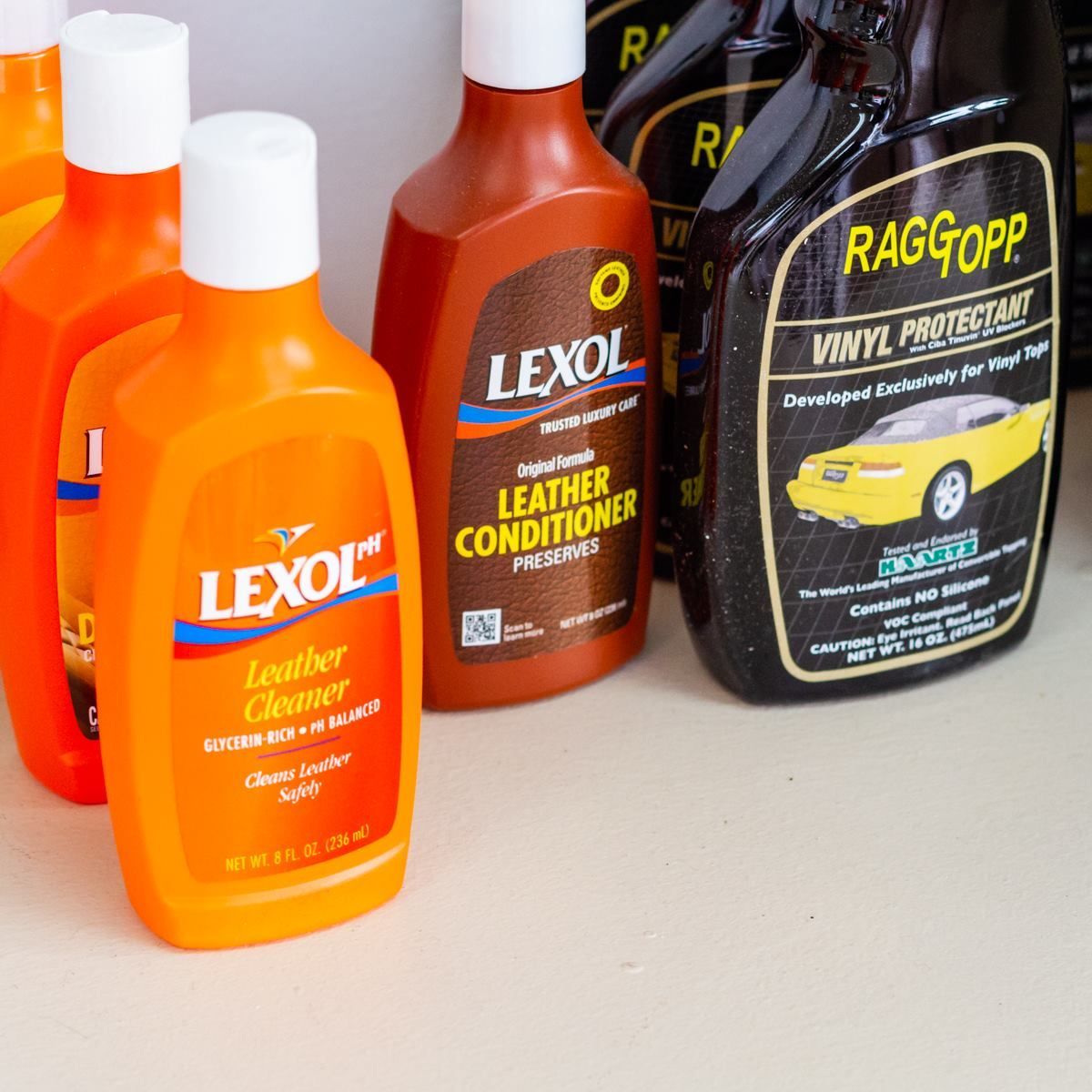 A bottle of lexol leather conditioner sits next to a bottle of raggapp