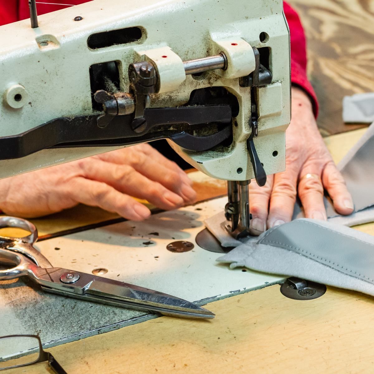 A person is using a sewing machine with scissors on the table