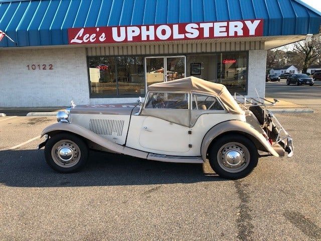 A white car is parked in front of lee 's upholstery