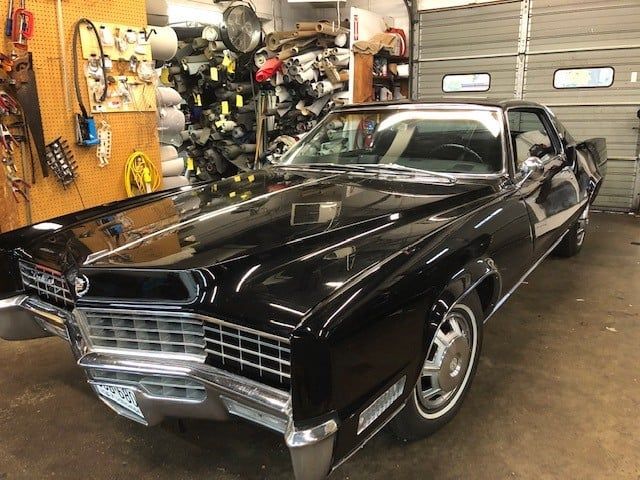 A black car is parked in a garage next to a garage door.