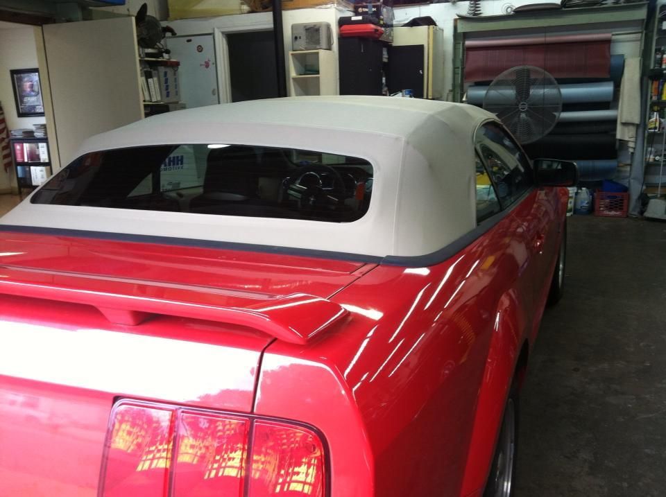 A red car with a white top is parked in a garage