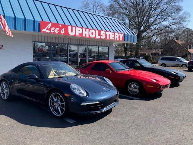 Three sports cars are parked in front of lee 's upholstery