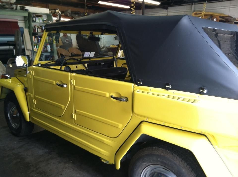 A yellow car with a black top is parked in a garage