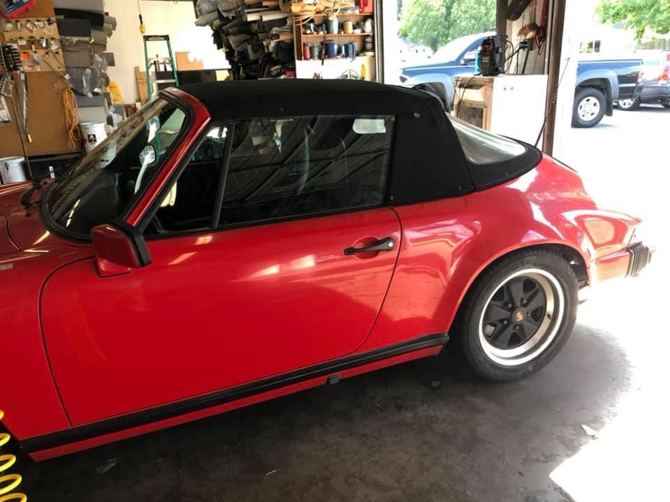 A red car with a black top is parked in a garage.