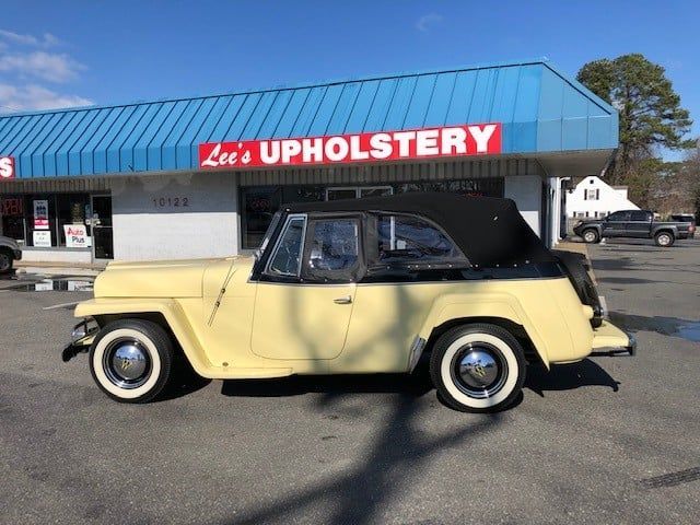 A yellow car is parked in front of lee 's upholstery