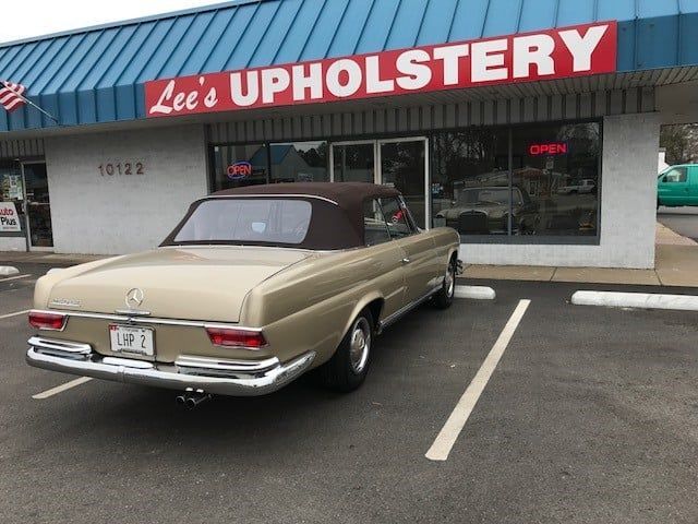 A car is parked in front of lee 's upholstery