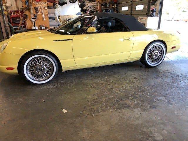 A yellow convertible is parked in a garage.
