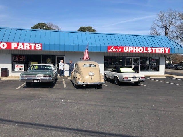 Three cars are parked in front of lee 's upholstery