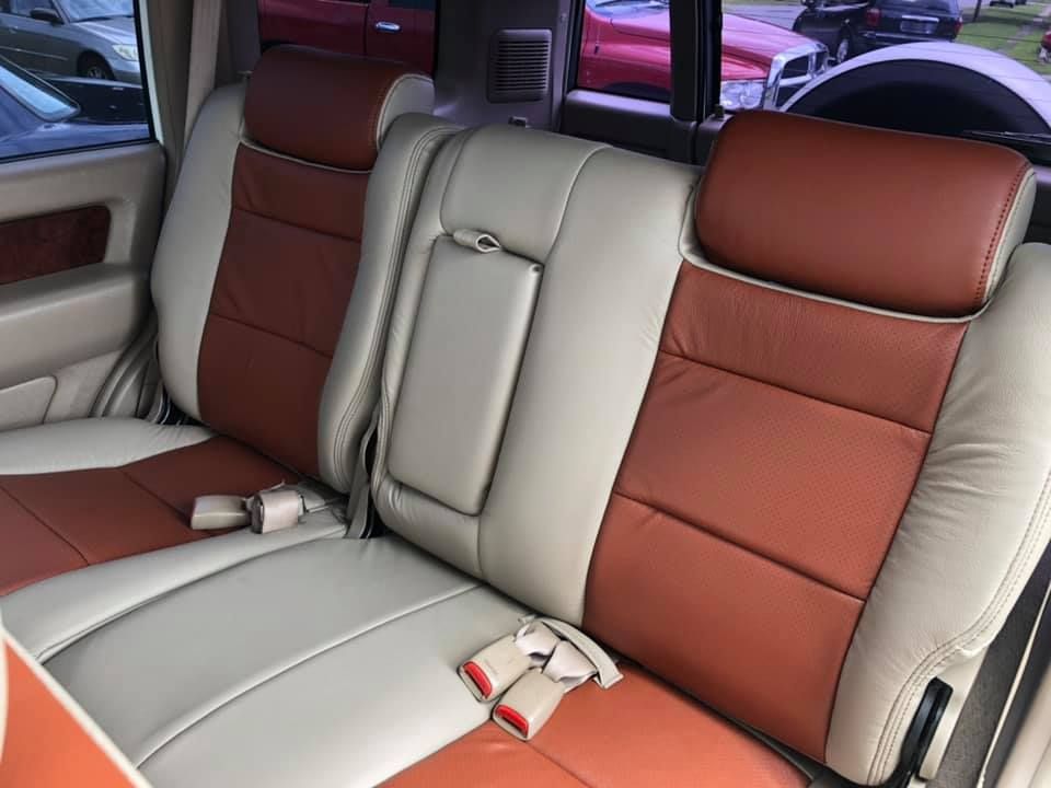 The back seat of a car with brown and white leather seats
