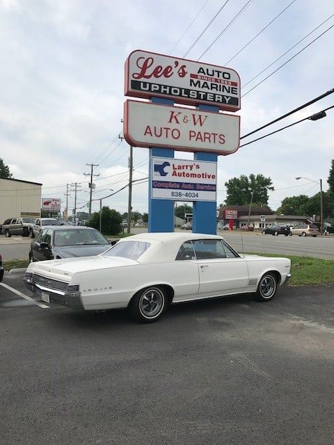 A white car is parked in front of a lee 's auto marine upholstery sign