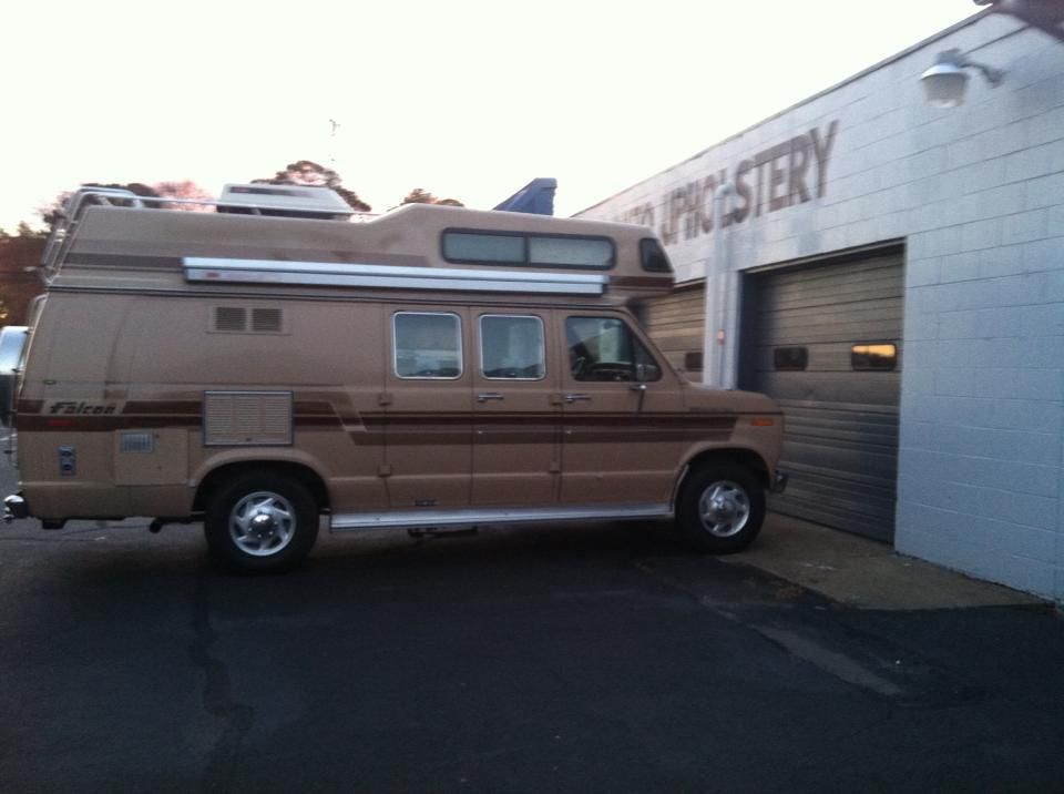 A van is parked in front of a building that says upholstery