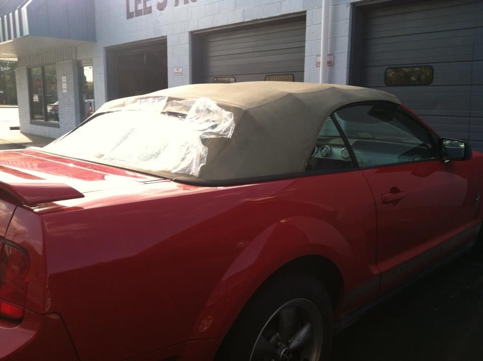 A red convertible is parked in front of a garage