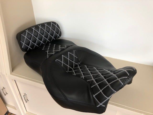 A black motorcycle seat is sitting on a shelf