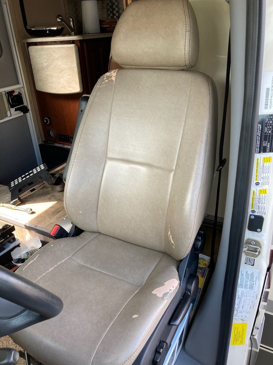 A tan leather seat in a car with a steering wheel.