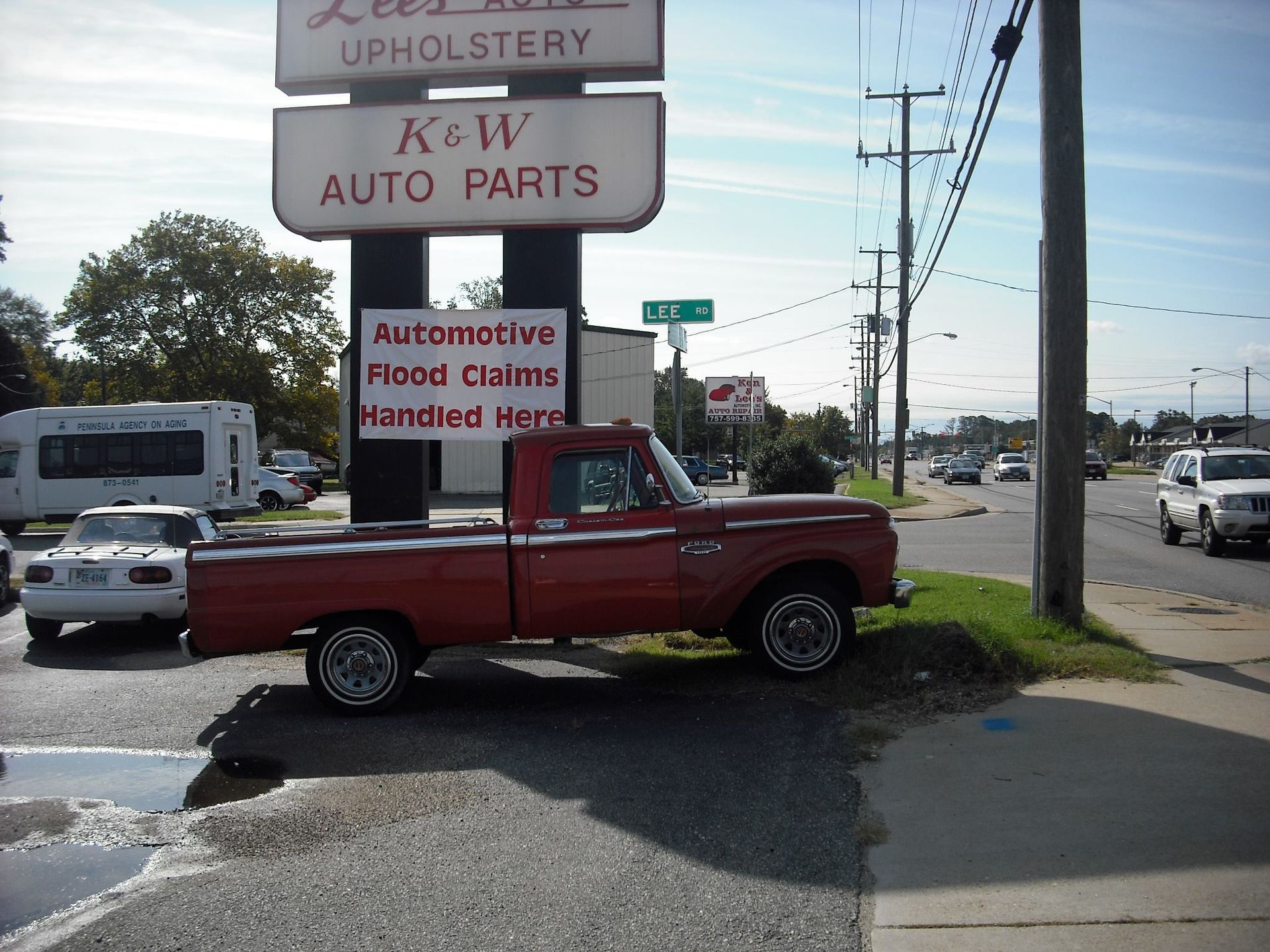 A red truck is parked in front of a sign for ksw auto parts