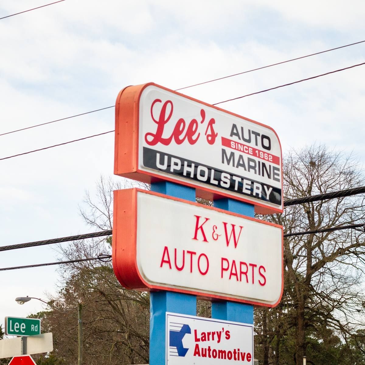 A sign for lee 's auto marine upholstery and kew auto parts