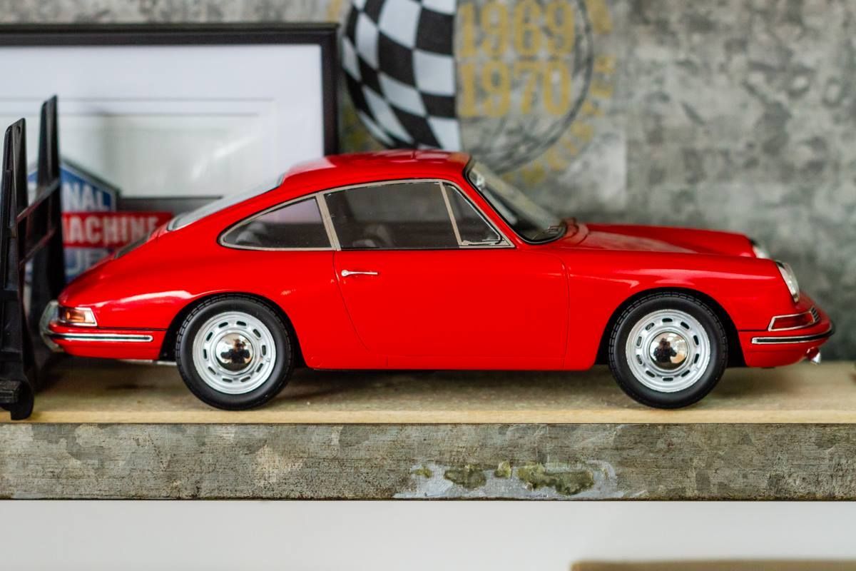 A red porsche 911 model car is sitting on a shelf.