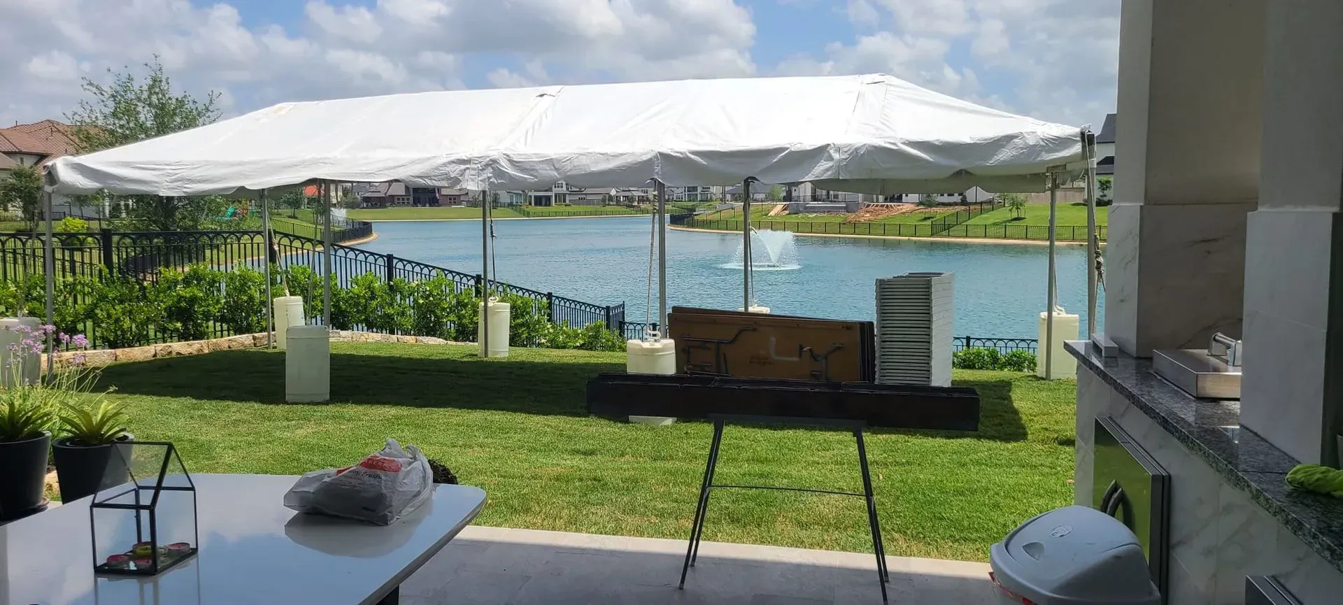 Backyard event with tent over table on grass by lake.