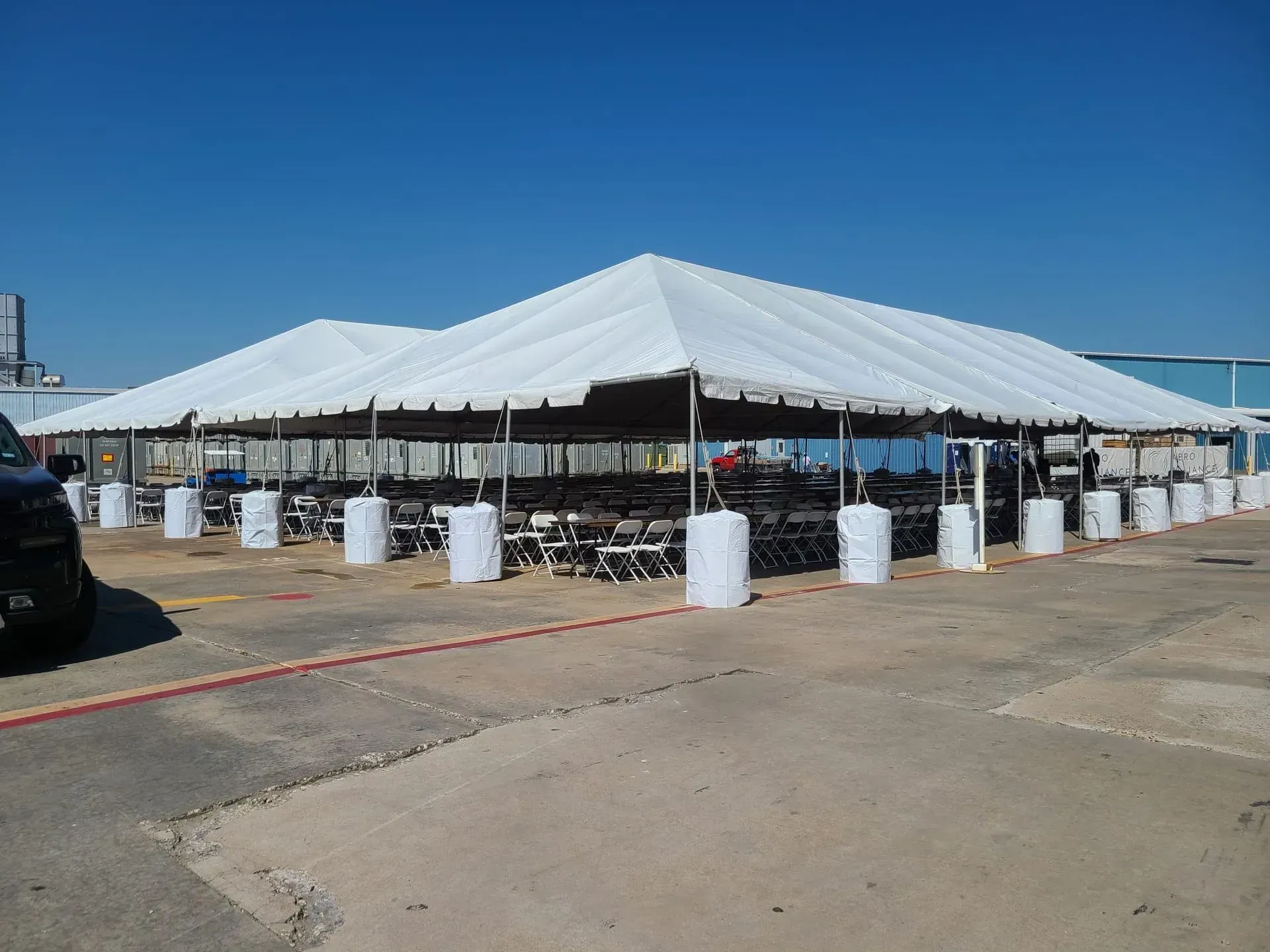 Large white tents set up outdoors, with tables and chairs inside, on a clear day.