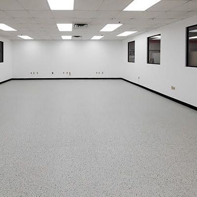 An empty room with a gray floor and white walls