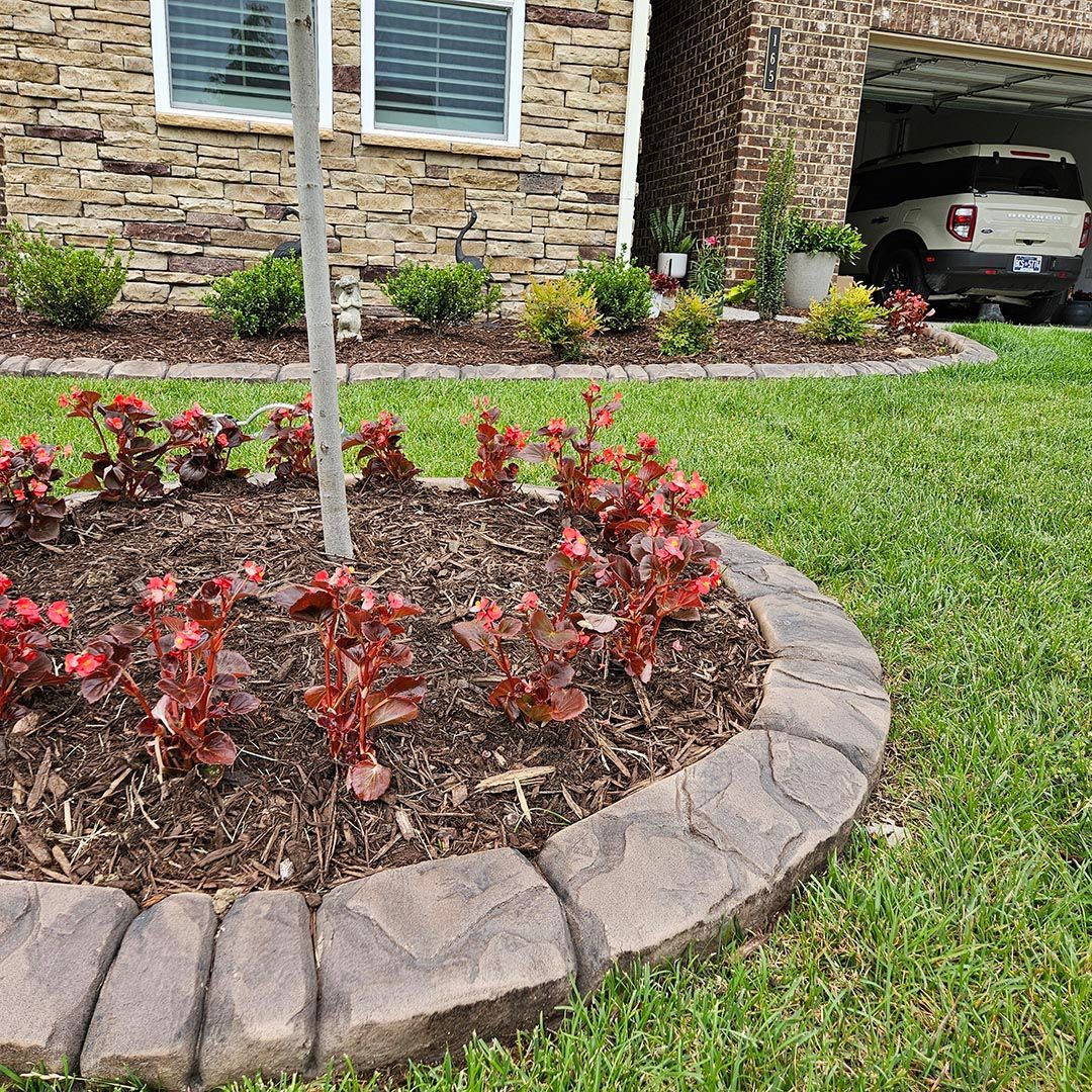 A flower bed in front of a house with Chattanooga rock curb.