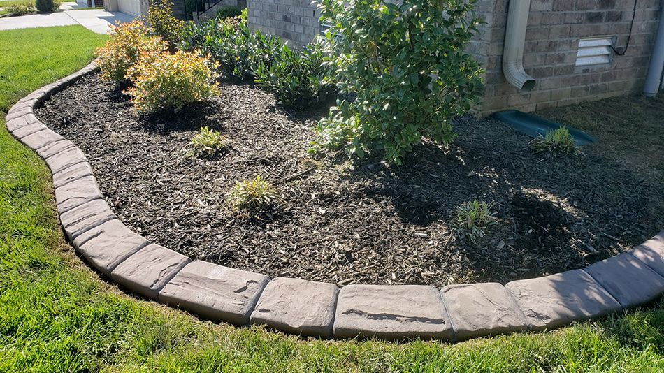 A brick border surrounds a garden in front of a house.