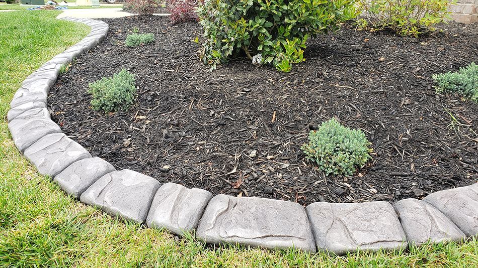 A garden with a stone border and a tree in the middle.