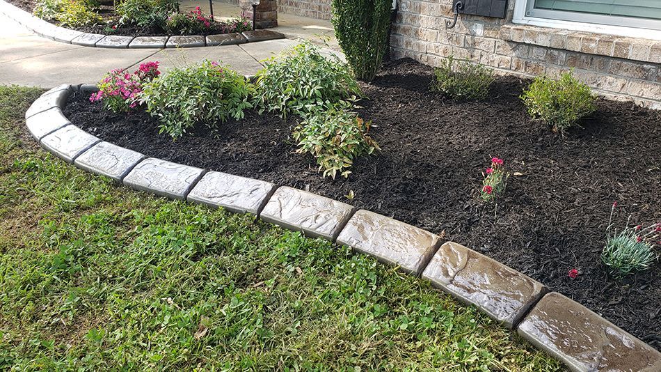 A lawn with a stone curb and a garden in front of a house.