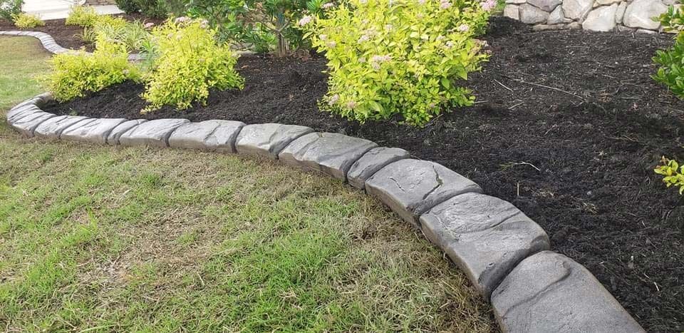 A lawn with a stone border and a bush in the middle of it