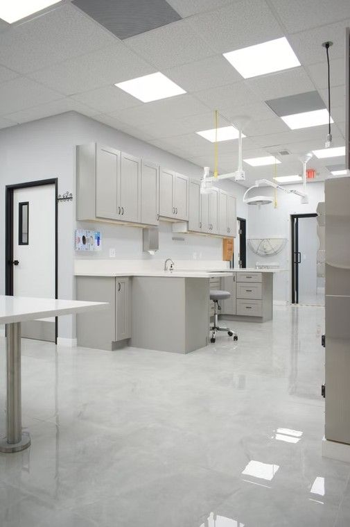 A modern veterinary operating room with white walls, cabinets, and glossy floor.