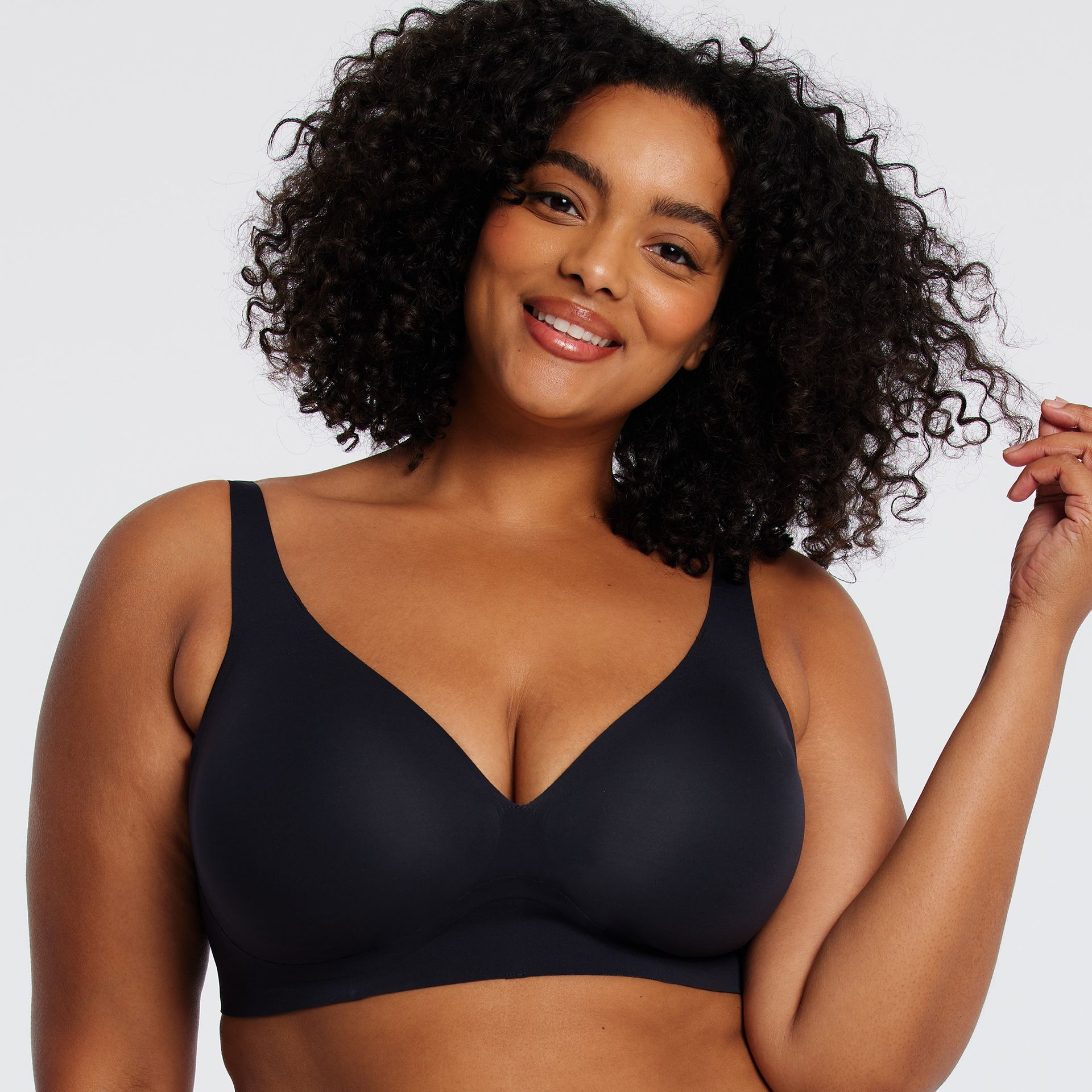A woman with curly hair is wearing a black bra.