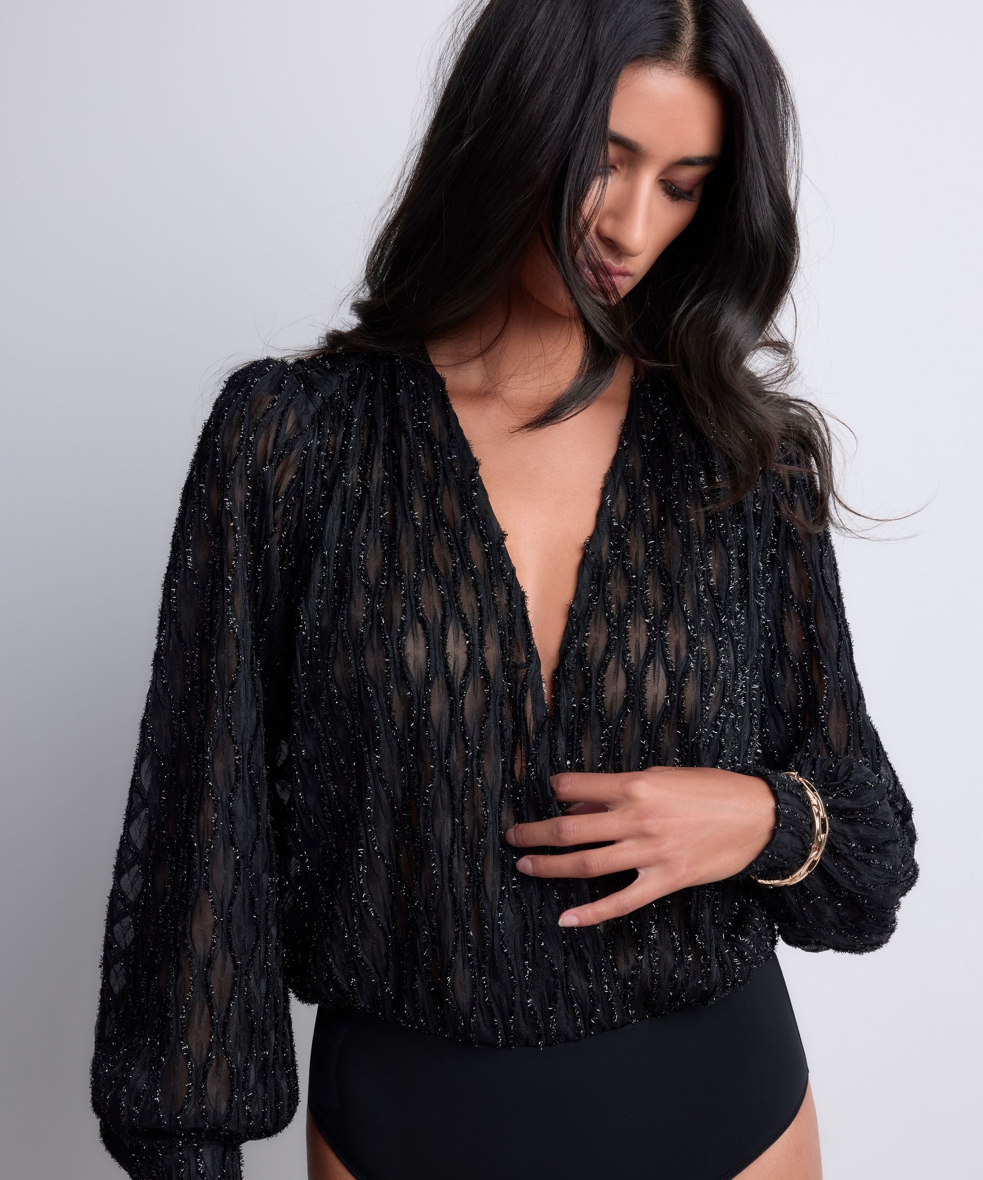 Woman in black sequined wrap top and bodysuit.