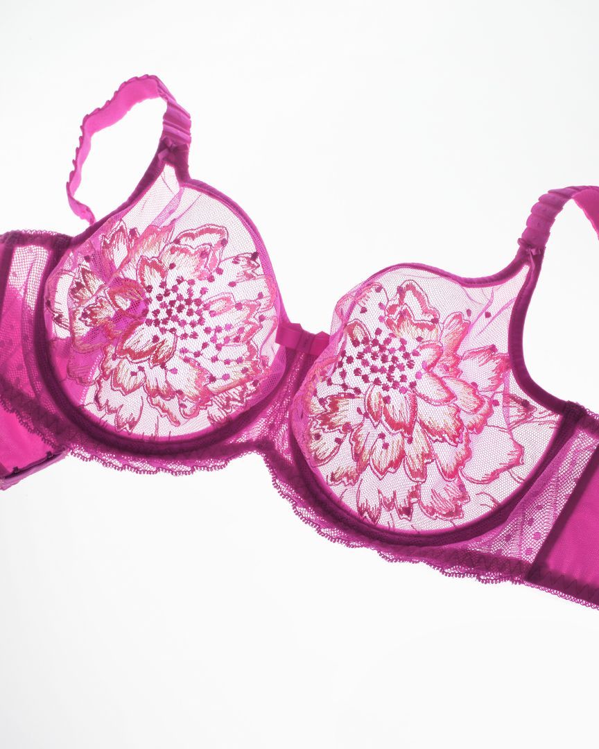 Pink lace bra with floral details, on a white background.
