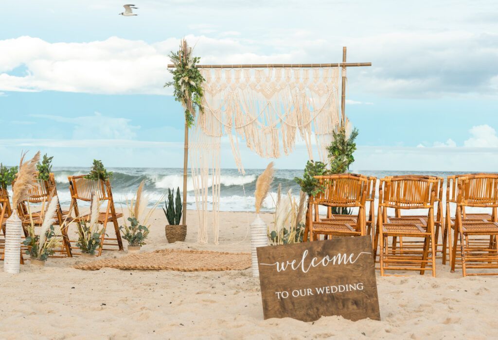 Beach wedding setup: wooden chairs, macrame backdrop, and a