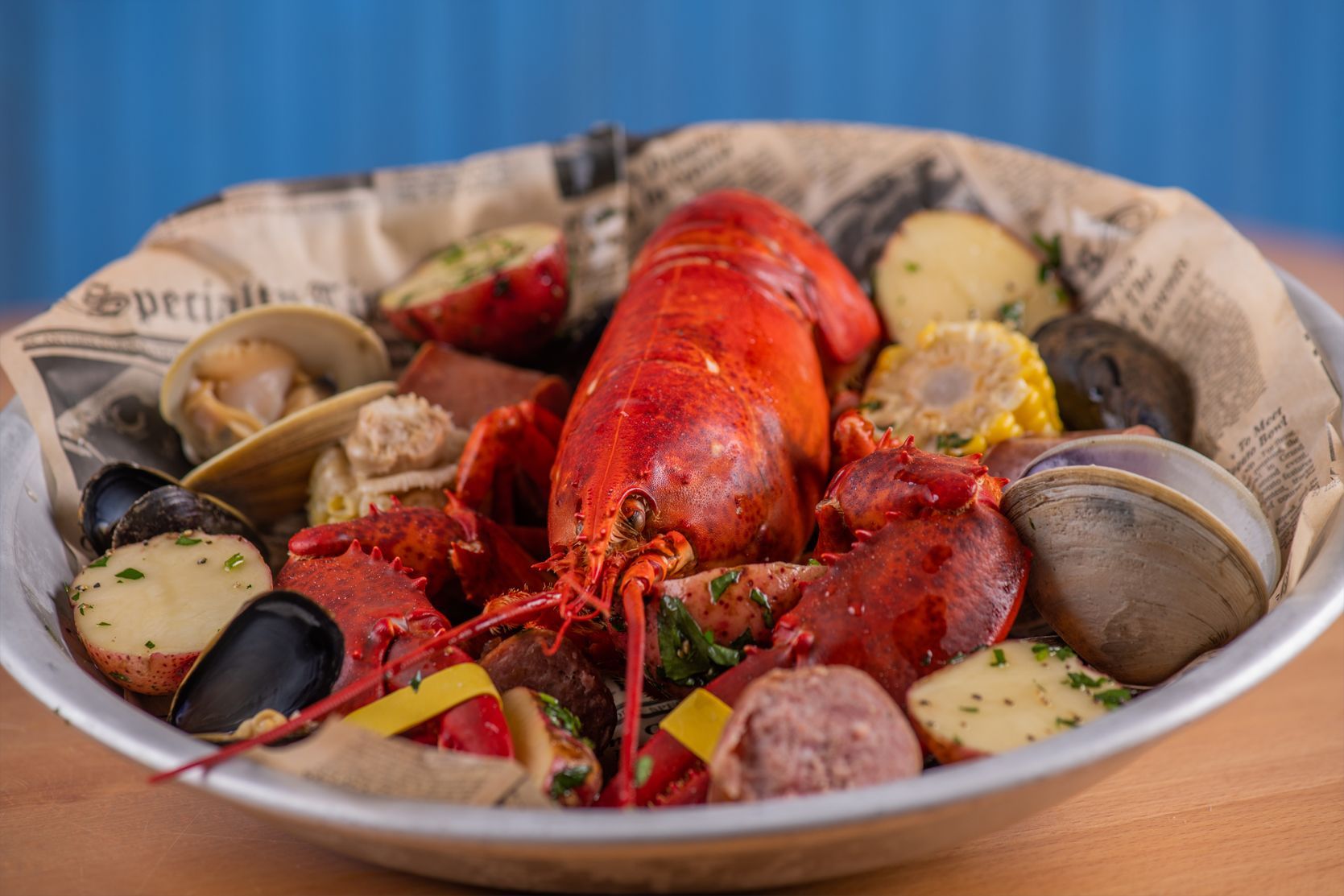 Lobster boil with lobster, potatoes, corn, sausage, clams, and mussels in a bowl.