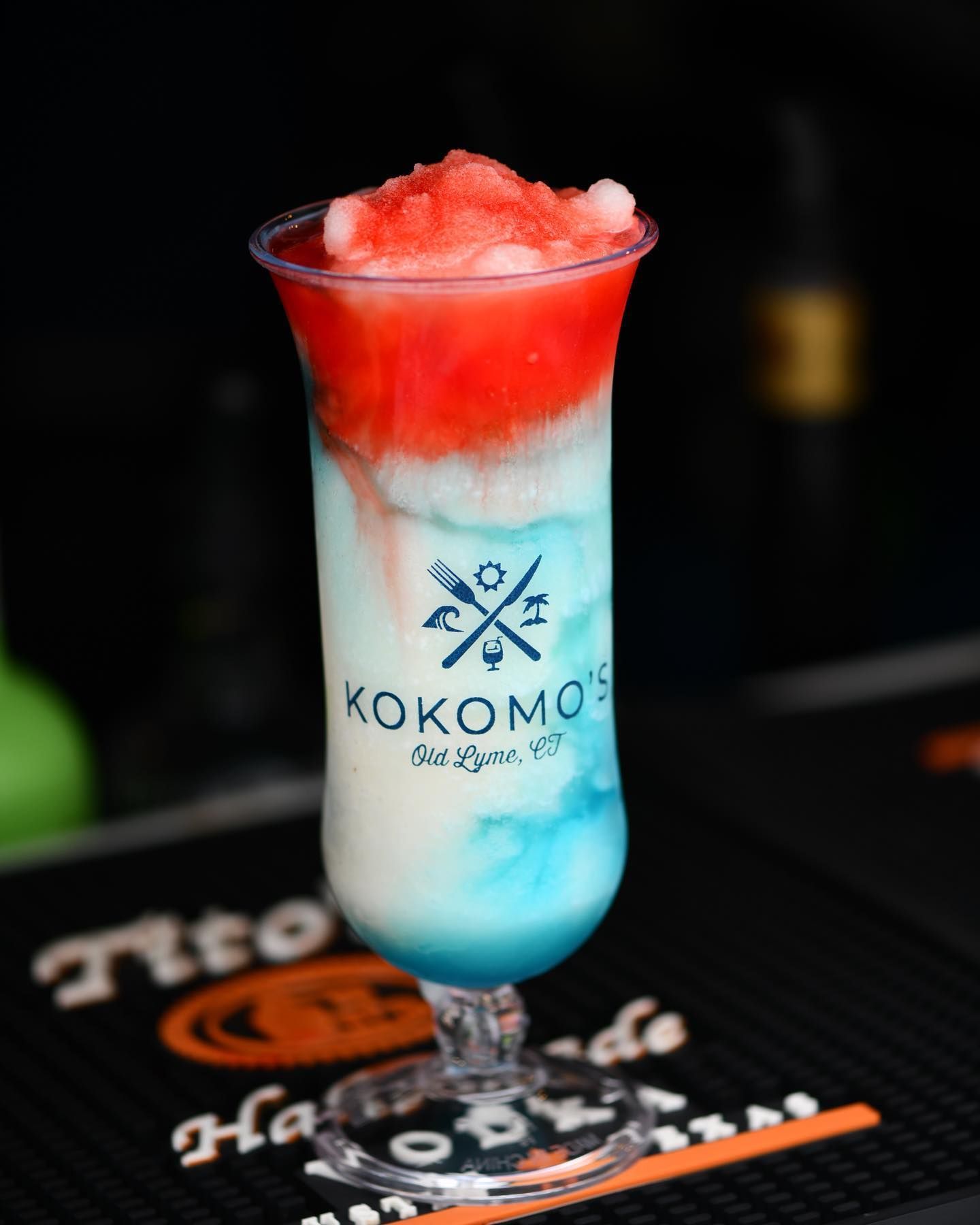 A red white and blue cocktail in a kokomos glass