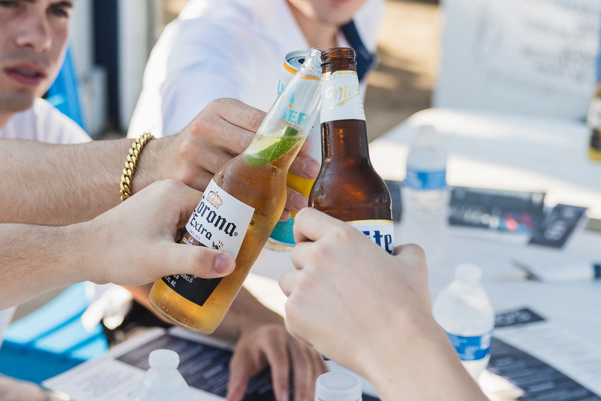 People toasting with beer bottles outdoors.