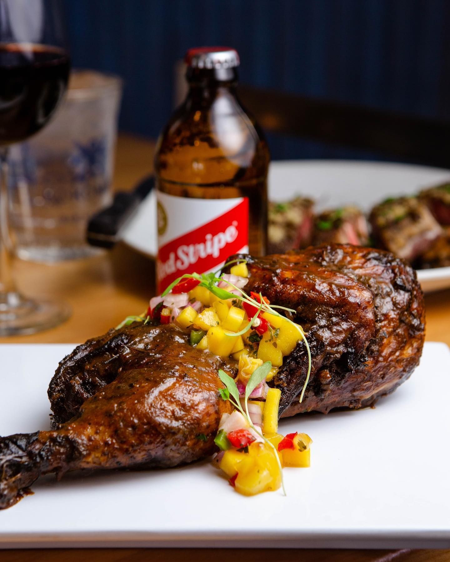 A plate of food with a bottle of red stripe beer in the background.