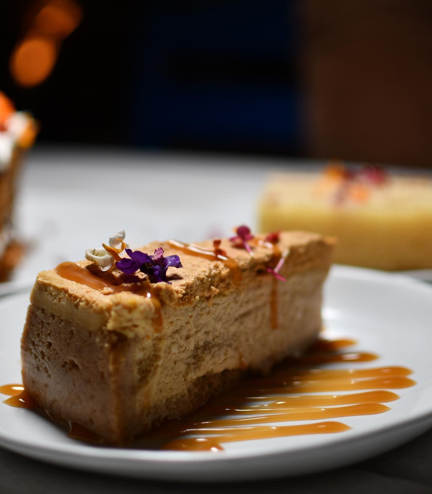A piece of cheesecake on a white plate with caramel sauce