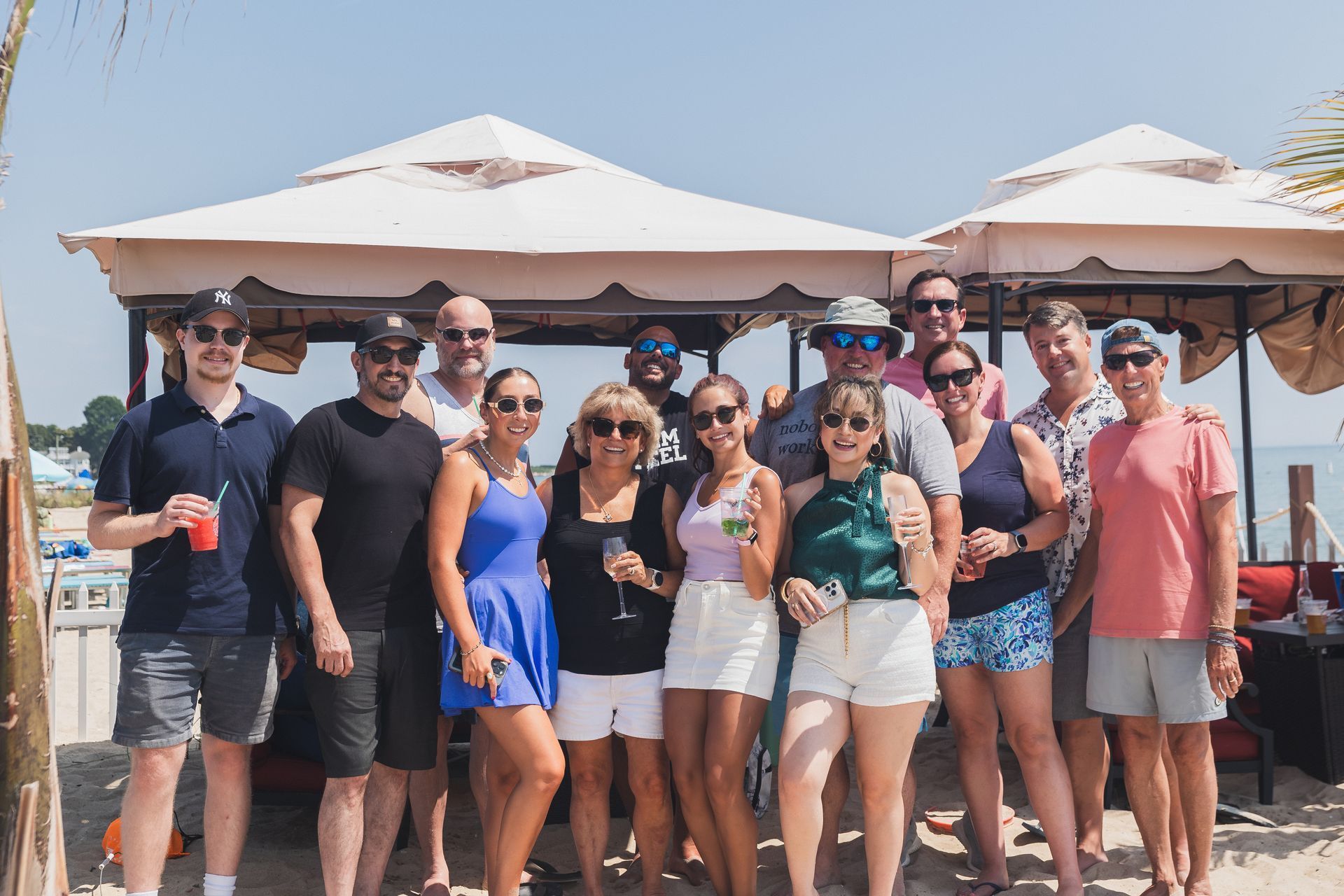 Rooftop scene with glass greenhouses, red couches, a fire pit, string lights, and cocktails at twilight.