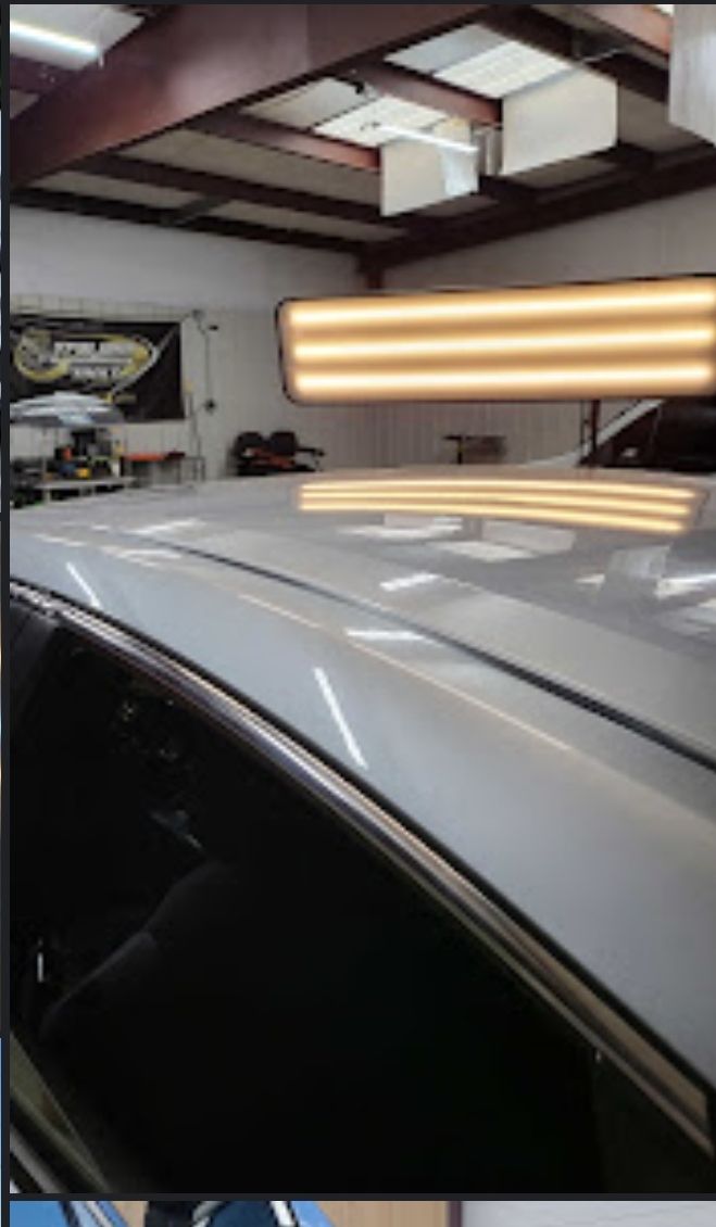 White car roof with dent, lit by a dent removal light in a repair shop.