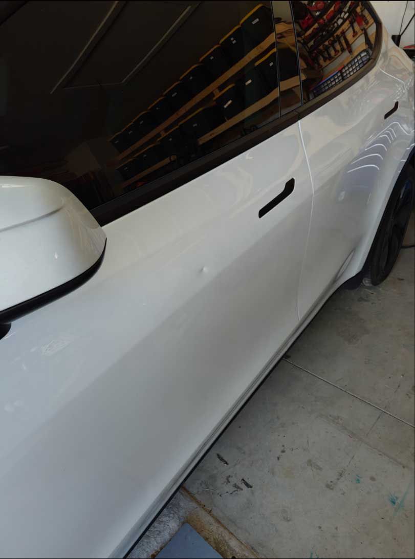 White car's side, showing a door handle and side mirror.