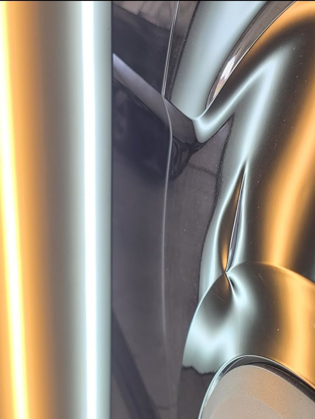 Reflections in shiny, dark material, showing distorted light and shapes.