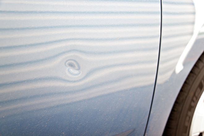 Blue car door with a dent.