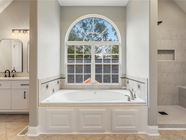 Modern white bathroom with a tub, shower, sink, window, and plant, dark gray tiled floor.
