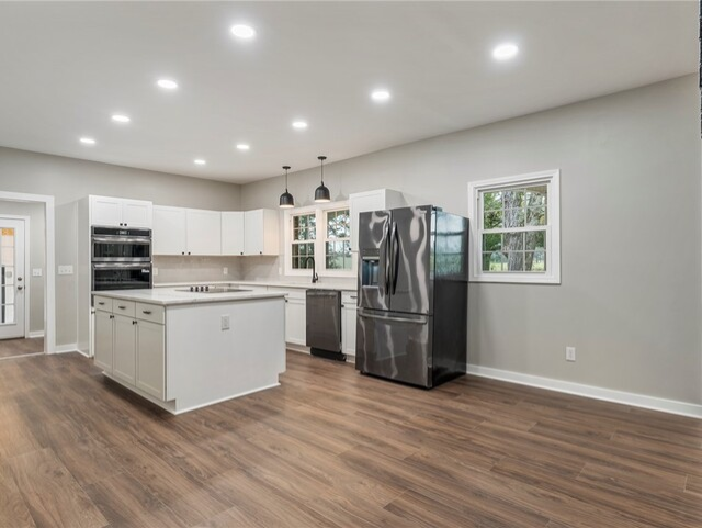 Modern kitchen with white cabinets, stainless steel appliances, and wood-look flooring.